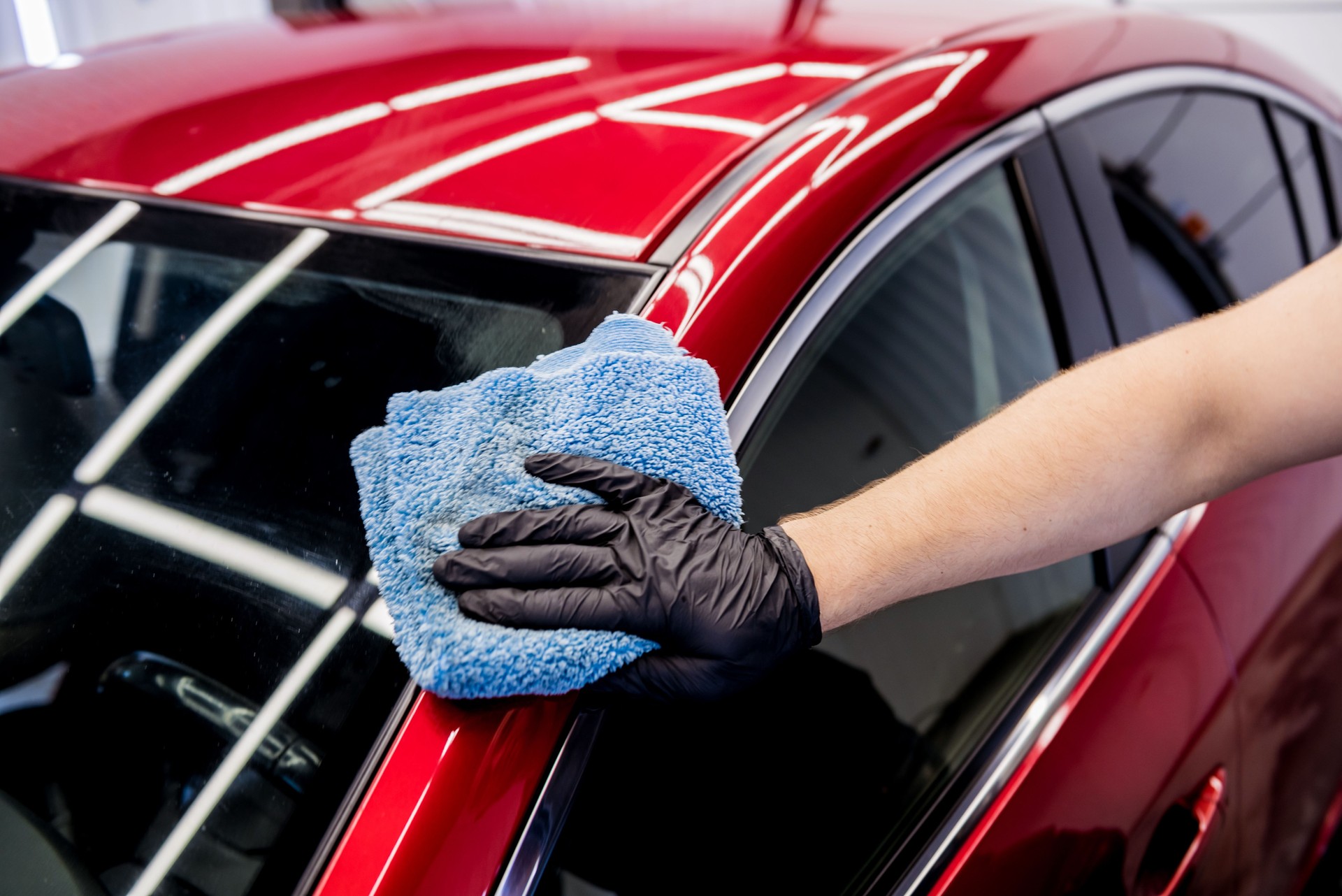 Car service worker polishing car with microfiber cloth.